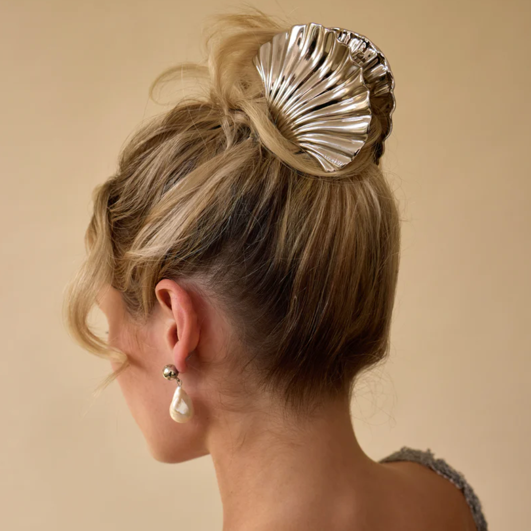 Glossy silver shell claw clip elegantly styled in a bun, perfect for securing hair in chic updos or casual looks.