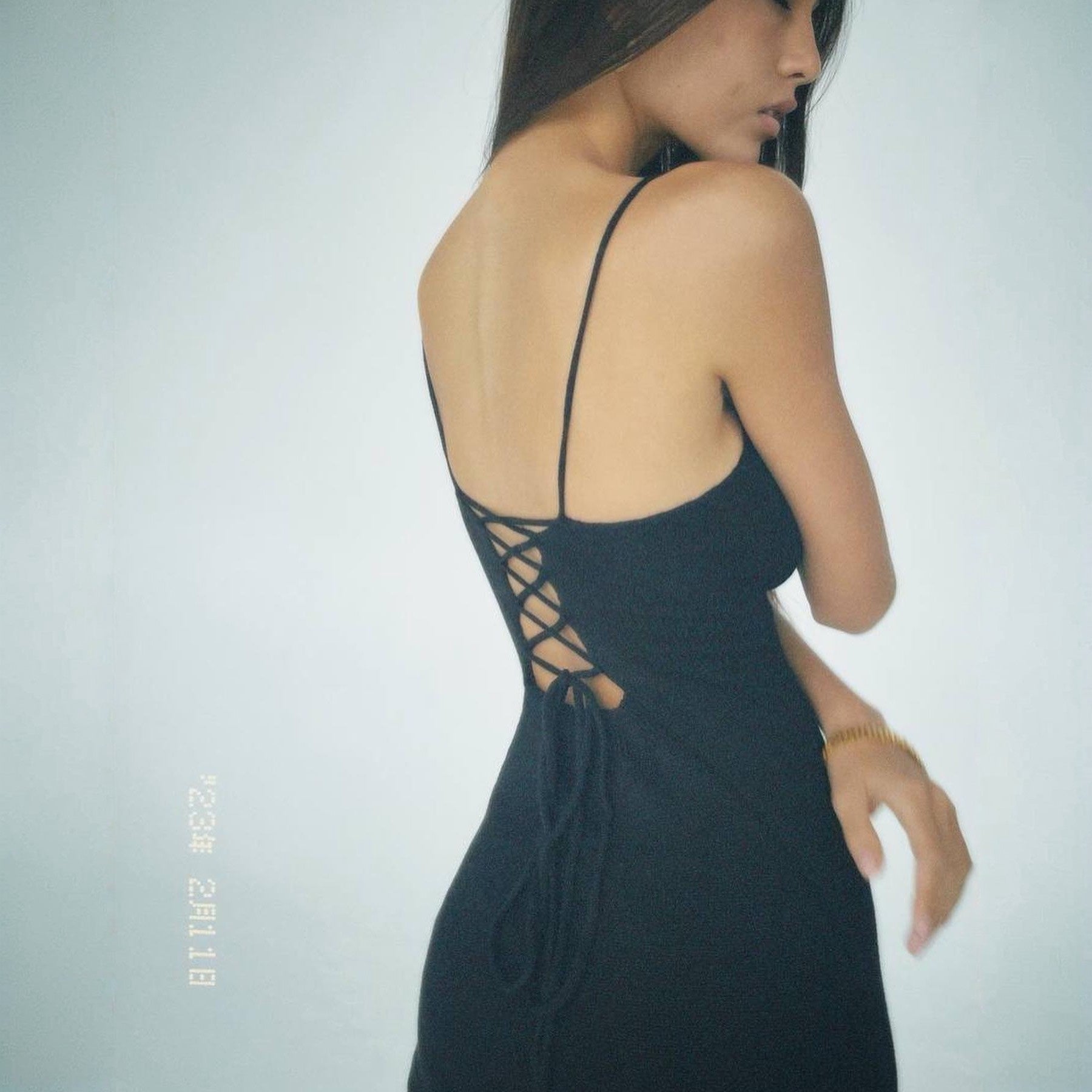 Black dress with open back worn by a model on a plain background