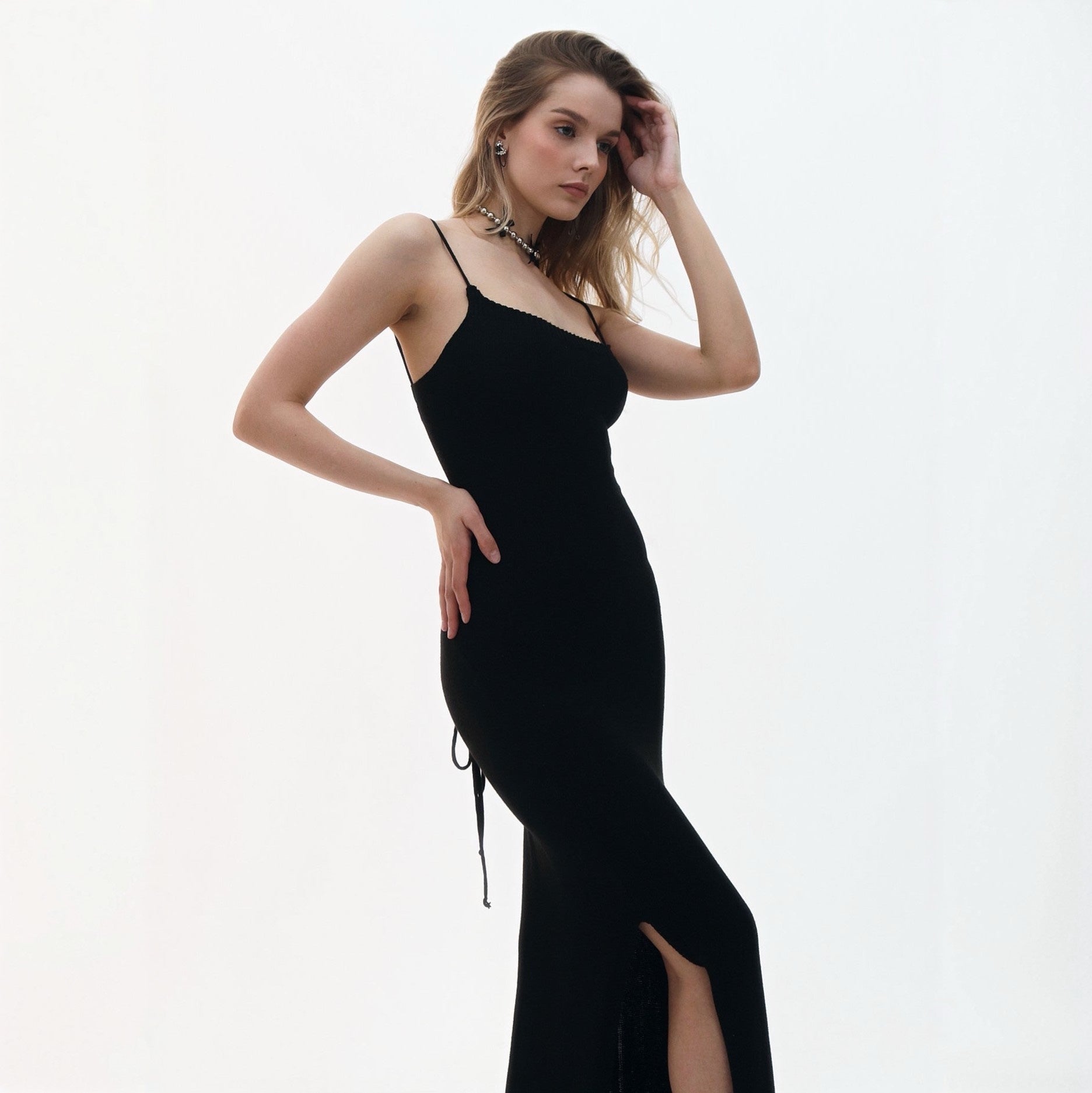 Woman wearing a black evening gown with a slit on a white background