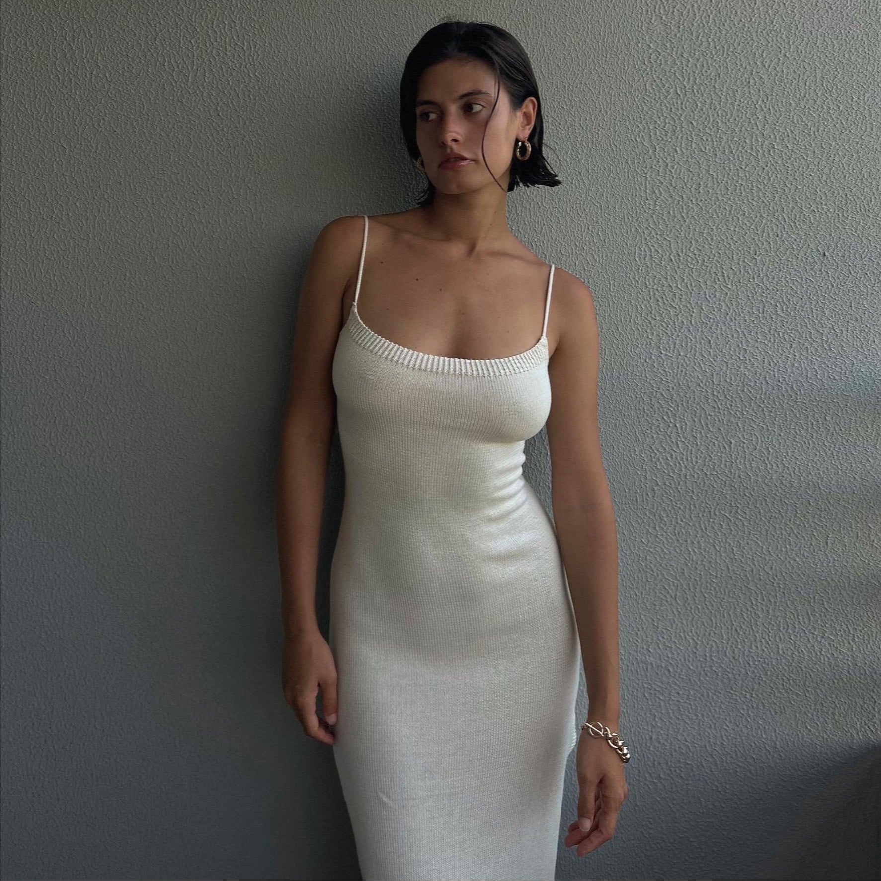 Woman wearing a white dress against a plain wall