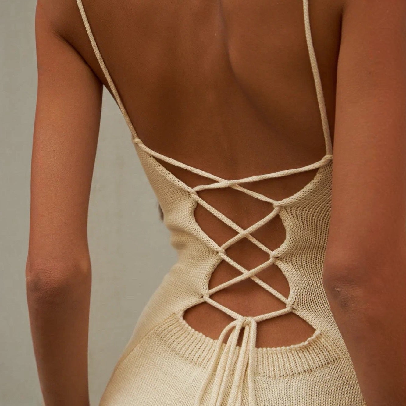 Beige knitted dress with open back on a neutral background