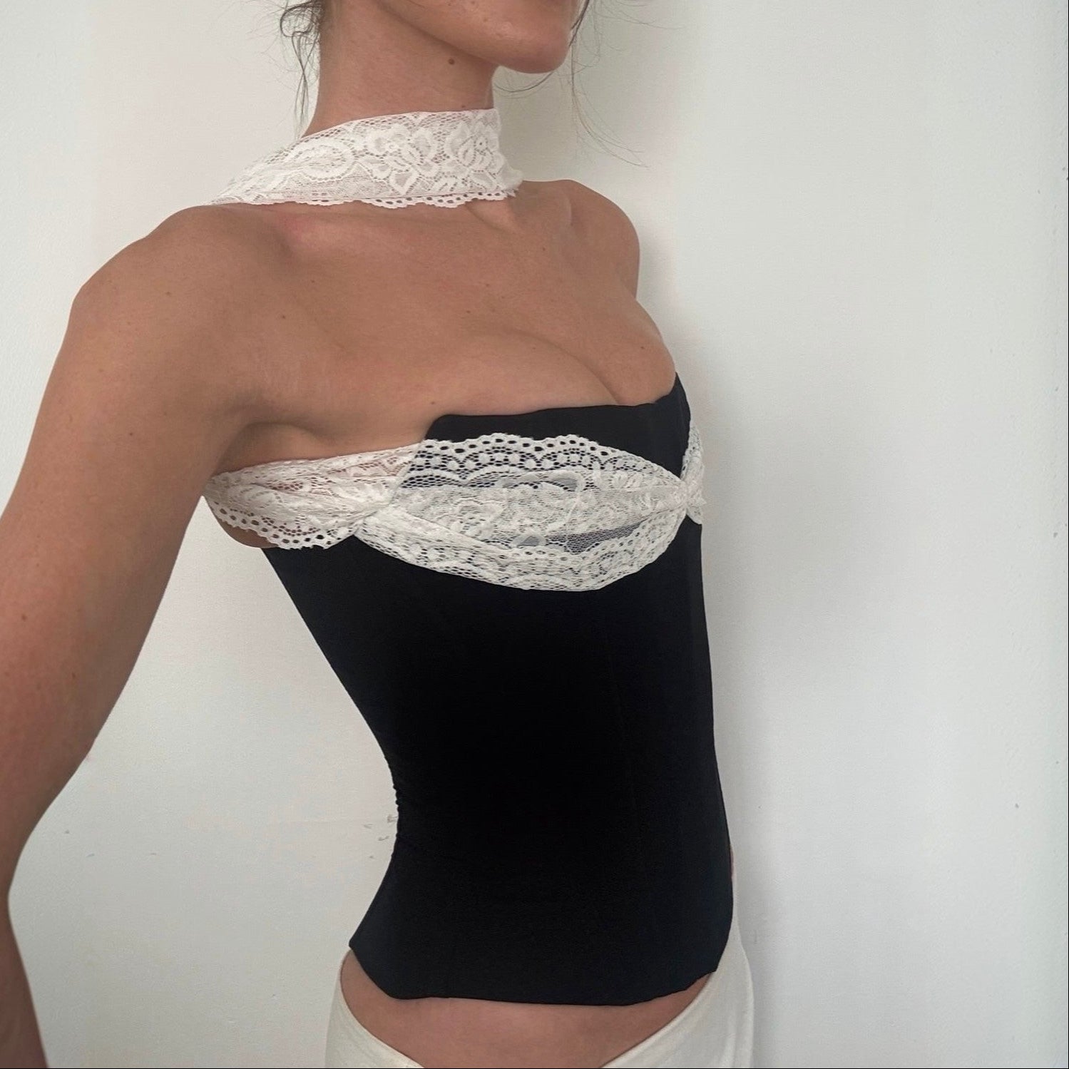 Black strapless top with white lace details on a plain background