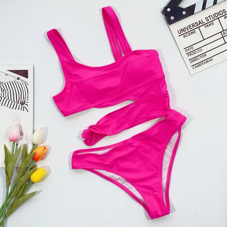 Pink swimsuit on a white surface with tulips and a clapperboard.