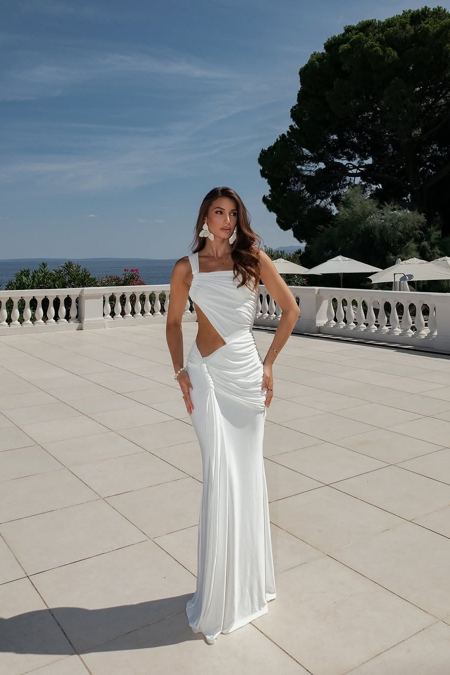Model wearing white one-shoulder maxi dress with asymmetric cut-out, front view