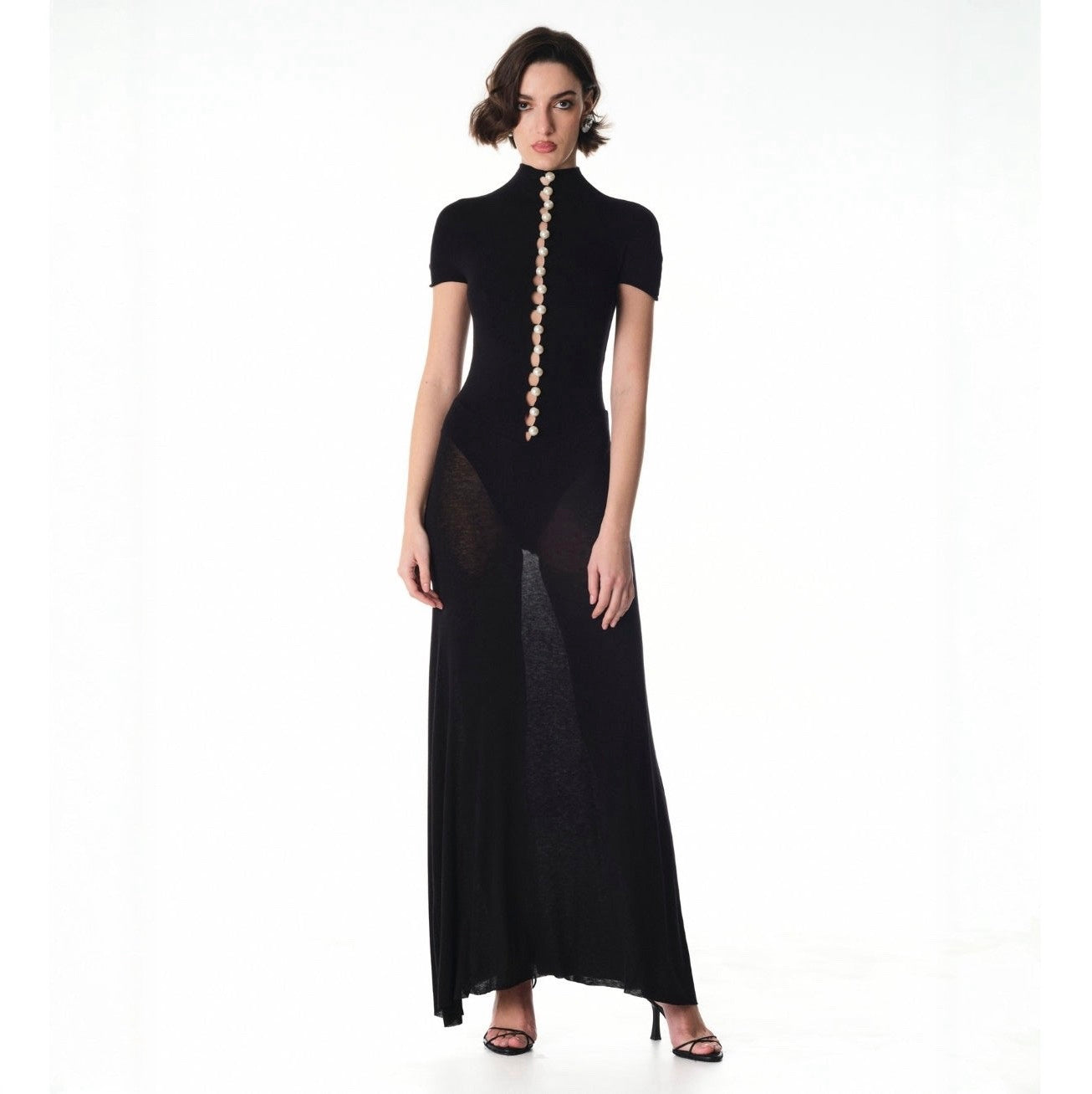 Woman wearing a black dress with a high neckline and long skirt on a white background