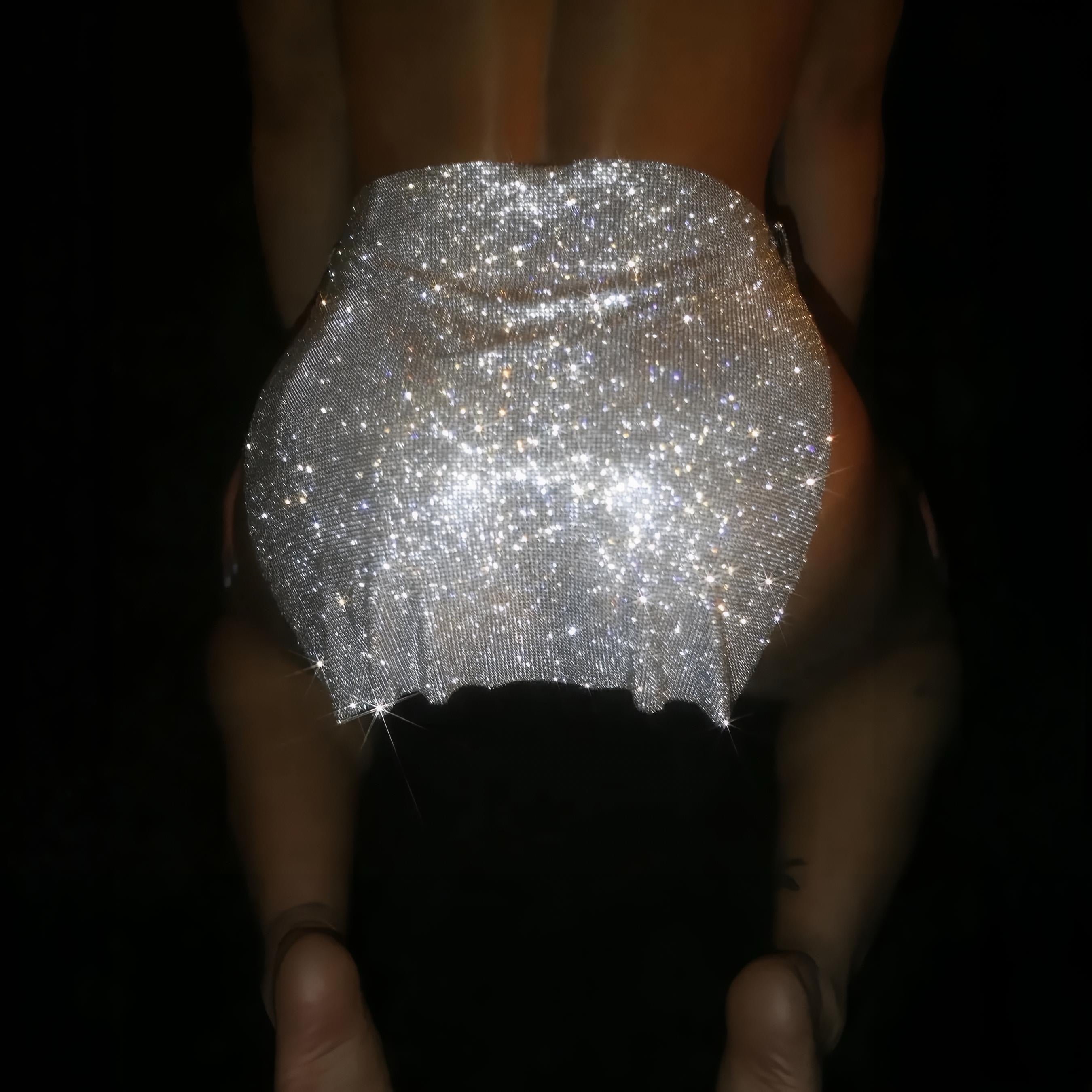 Person wearing a sparkling silver skirt against a dark background