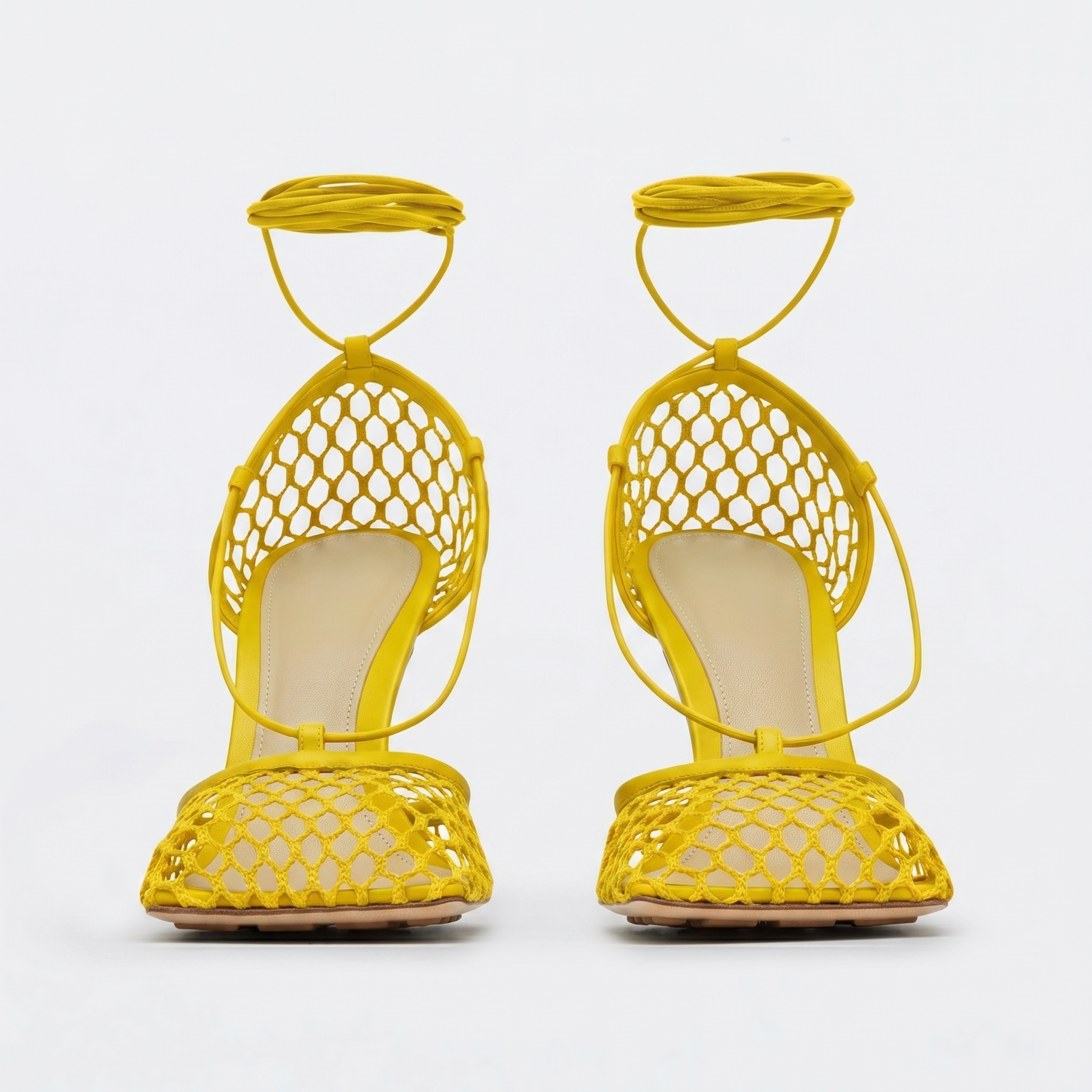 Yellow open-toe shoes with mesh design on a white background