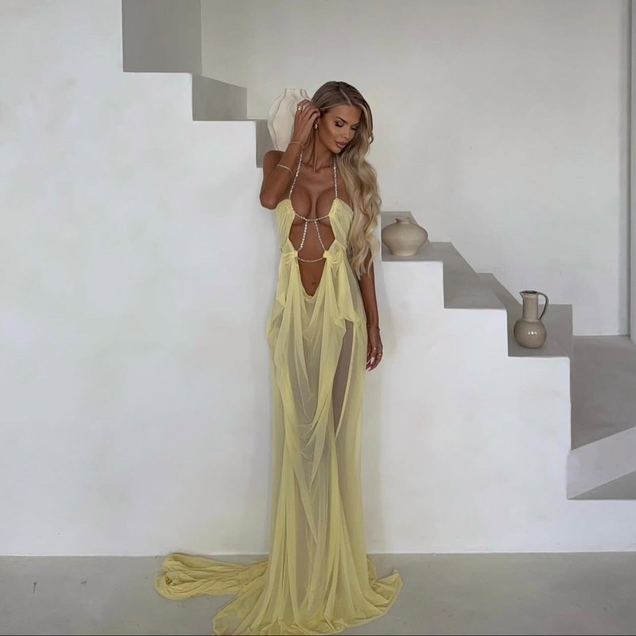 Woman in a yellow dress standing on a staircase in a minimalistic setting