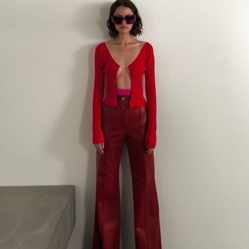 Person wearing a red outfit with a deep neckline against a plain background