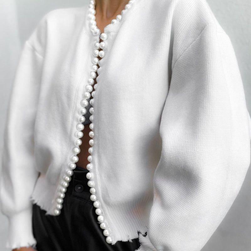 White cardigan with pearl buttons on a gray background