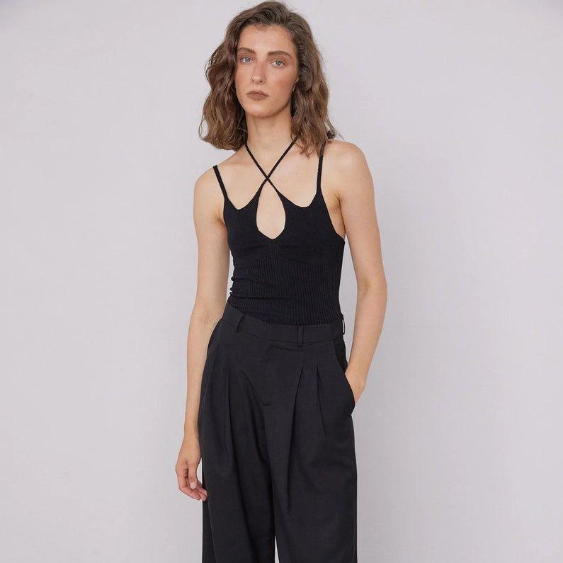 Woman wearing a black tank top and black pants against a plain background