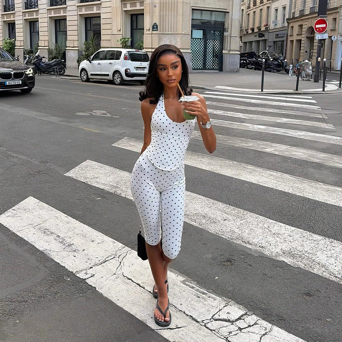 Woman in a polka dot dress crossing a street in an urban setting