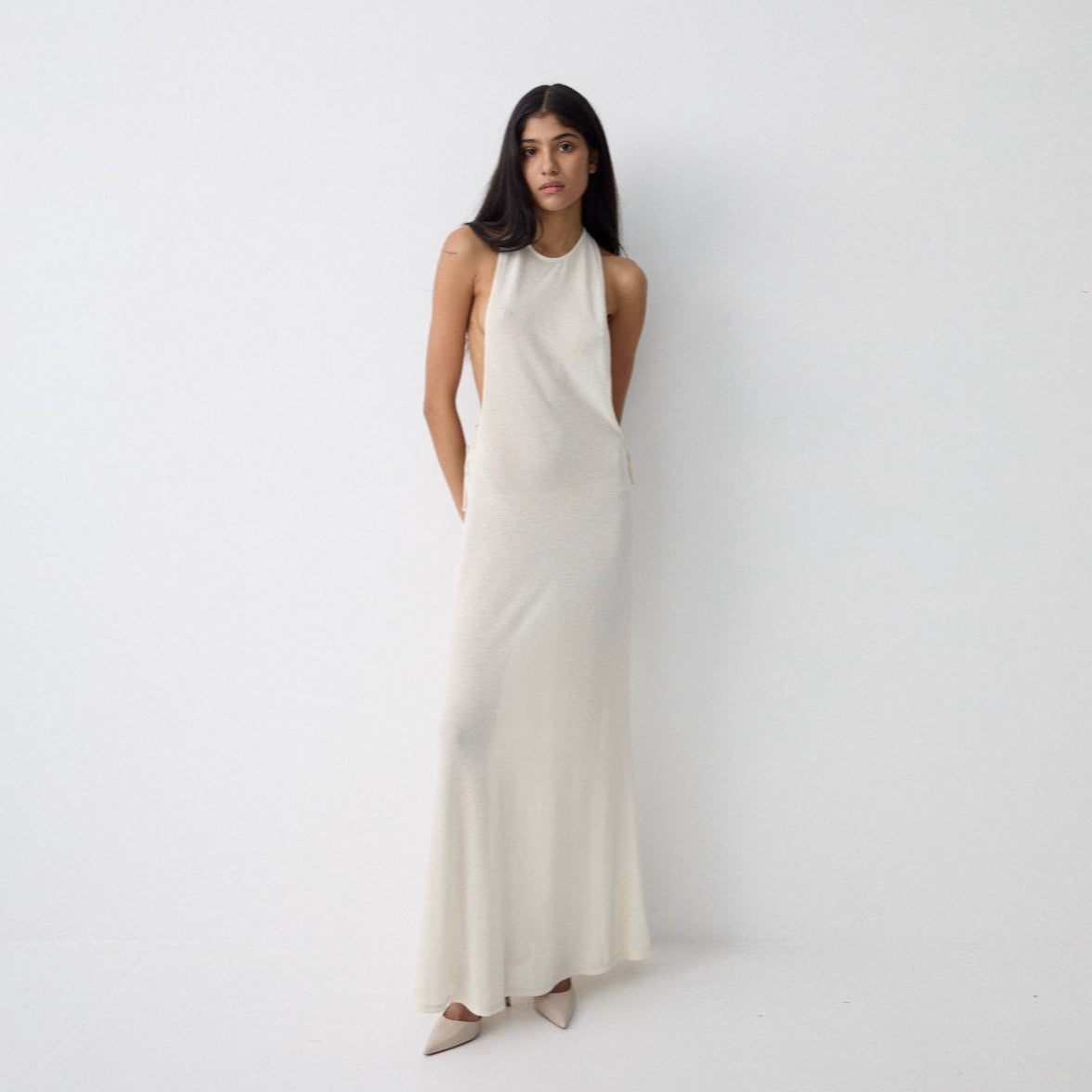 Woman wearing a white halter neck dress on a plain background