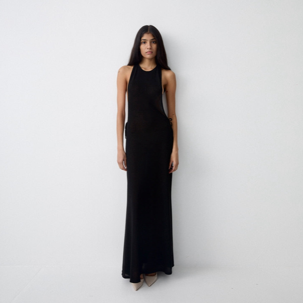 Woman wearing a black sleeveless dress against a white background