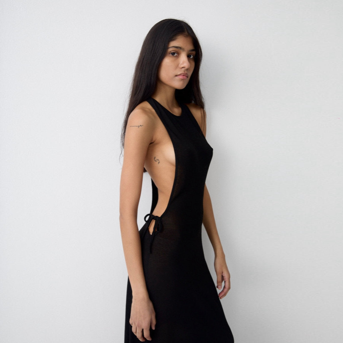 Woman wearing a black dress with cut-out design against a white background