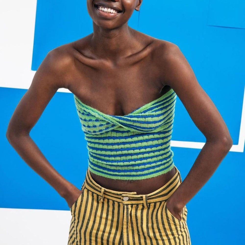Woman wearing a green and blue striped top with yellow and black striped pants against a blue background