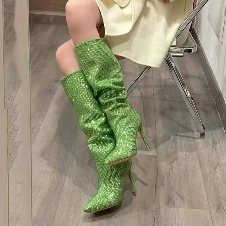Green glittery knee-high boots worn by a person sitting on a chair.