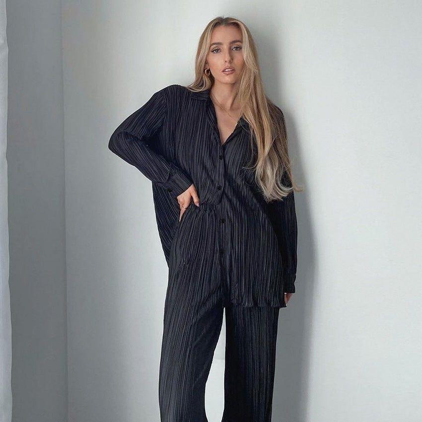 Woman wearing a black pleated outfit against a plain background