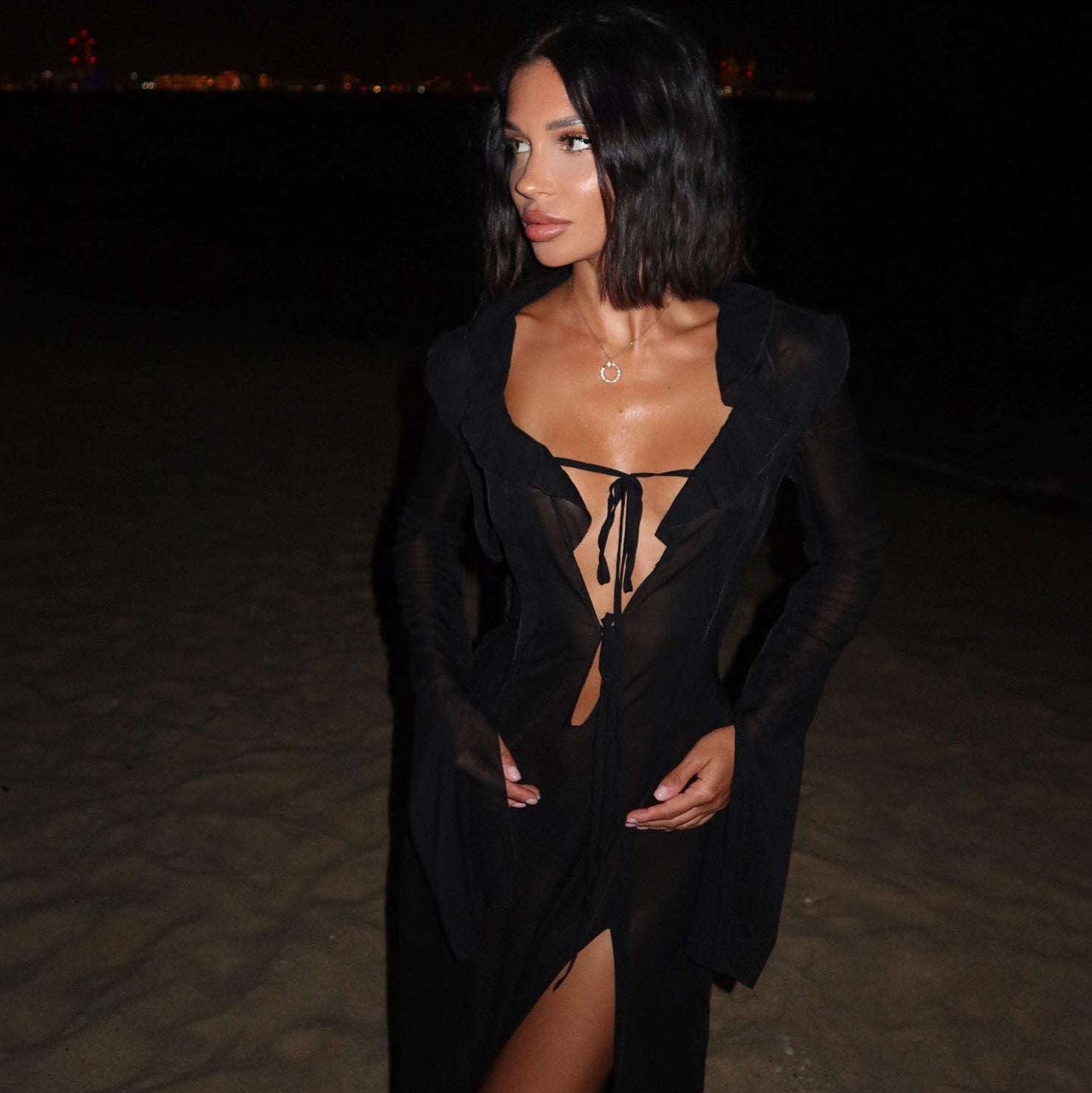 Woman wearing a black dress with cut-out design at night.