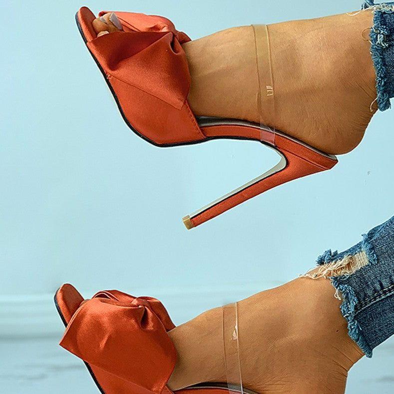 Brown high-heeled shoes with orange accents on a light blue background