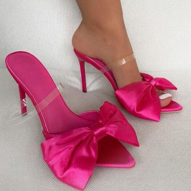 Pink high-heeled shoes with large bows on a light gray background