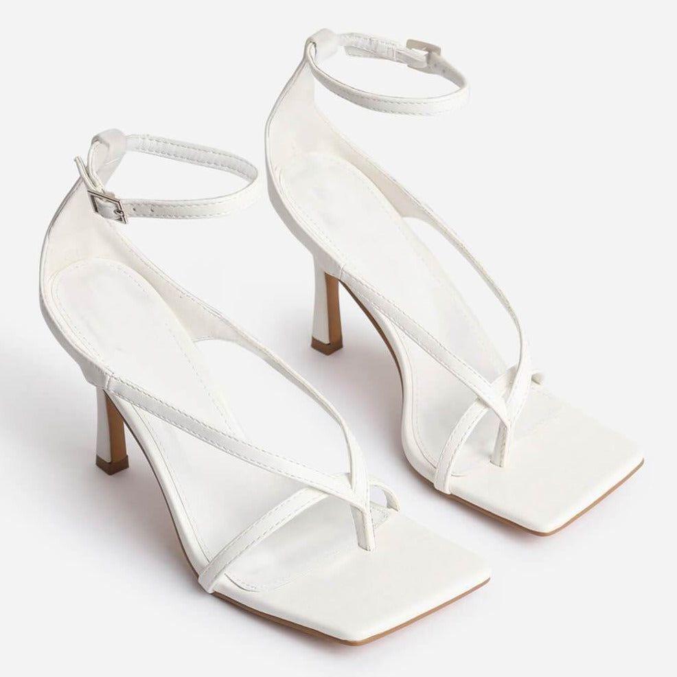 White high-heeled shoes with sheer straps on a white background