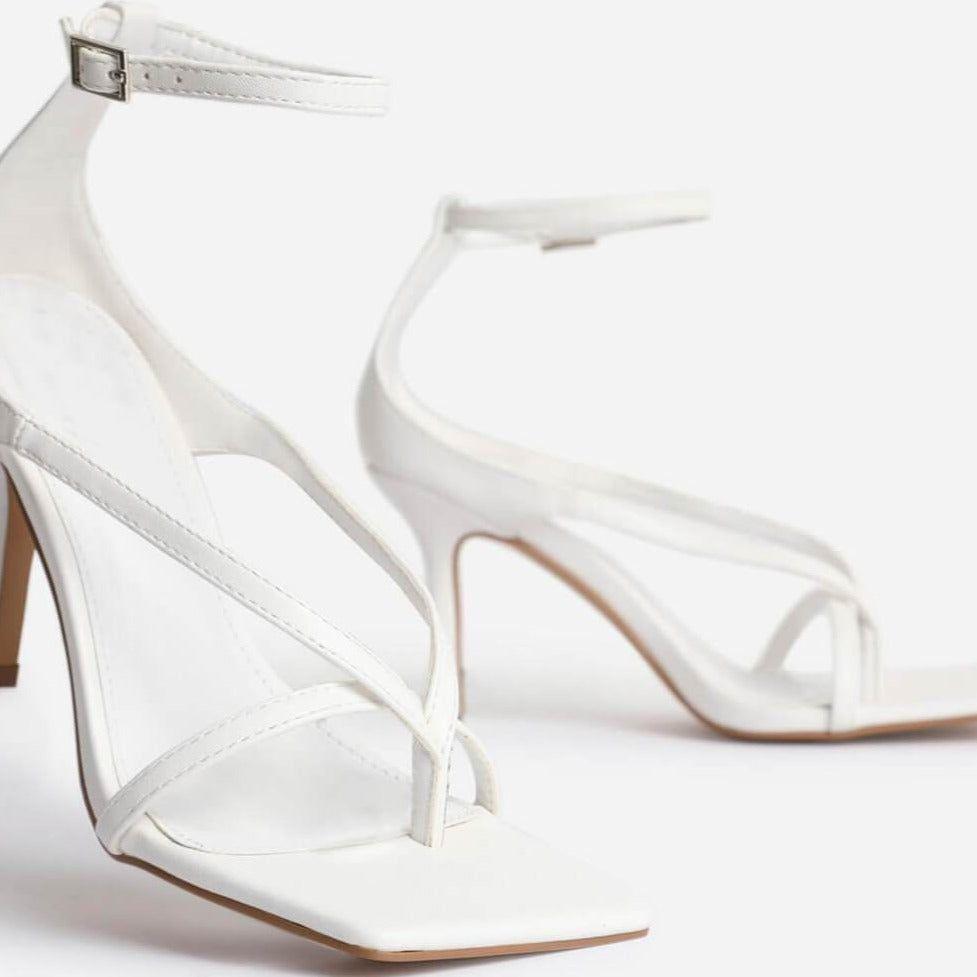 White high-heeled shoes with clear straps on a white background