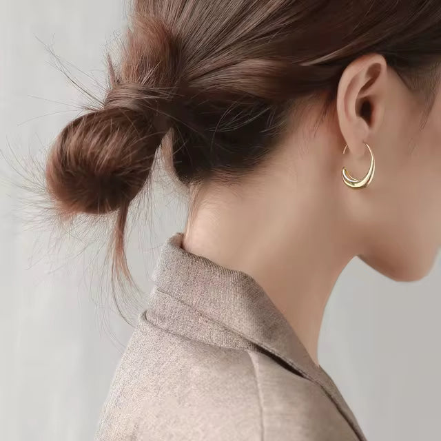 Elegant gold crescent hoop earrings, worn on a chic updo, adding sophistication to casual or formal outfits.