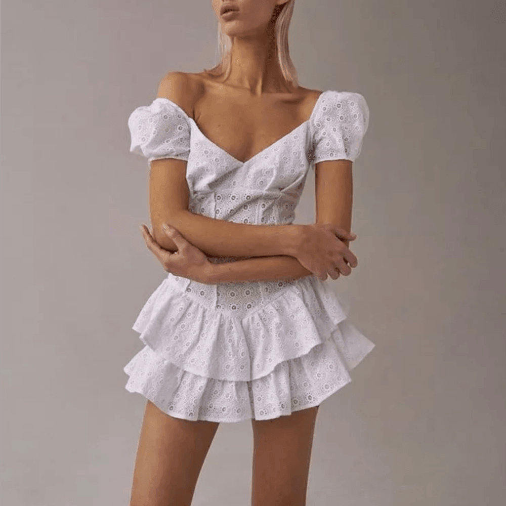 Woman wearing a white lace dress against a neutral background