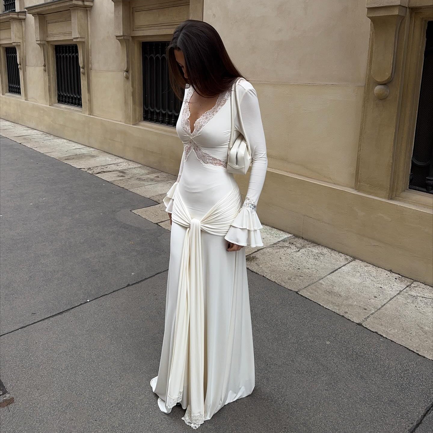 Woman in a white dress standing on a street with a building in the background