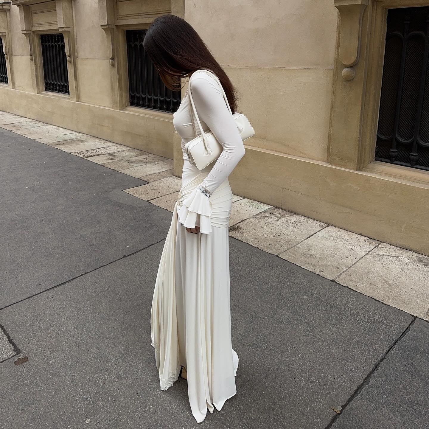 Woman in a white dress standing on a street with a building in the background