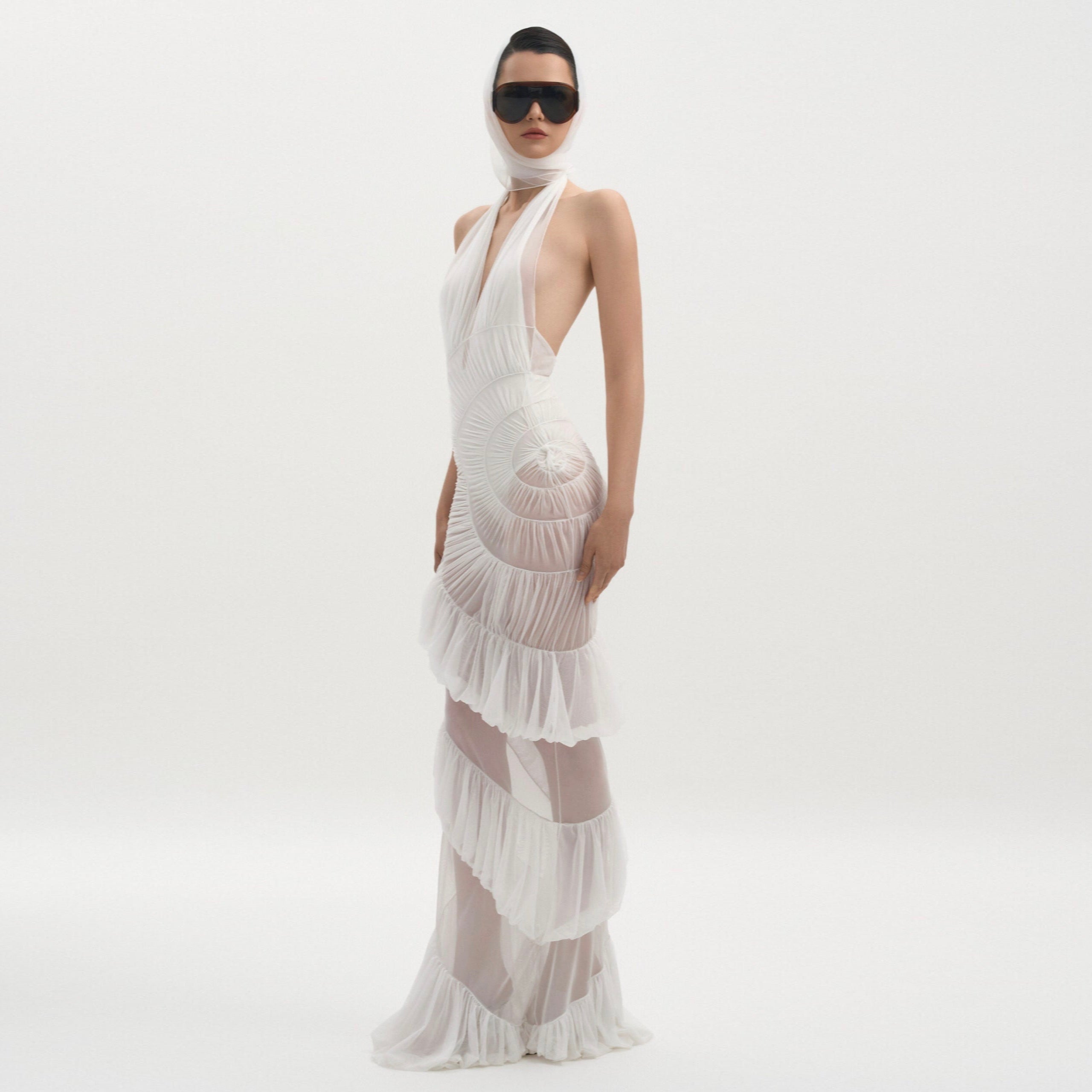 Woman wearing a white dress with ruffled layers on a white background