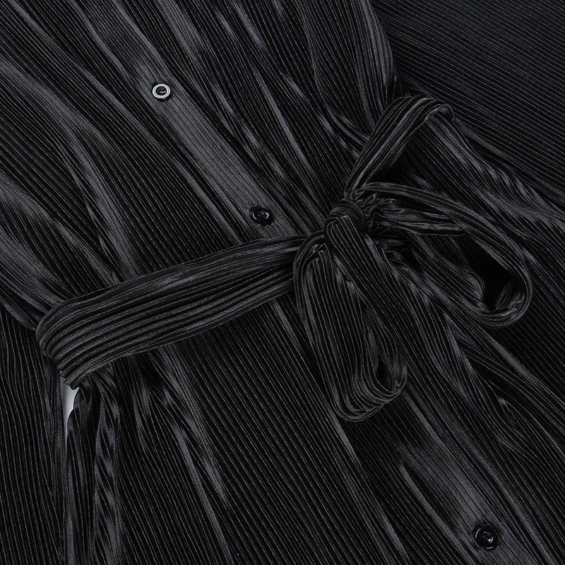 Close-up of a black pleated garment with a tie detail.