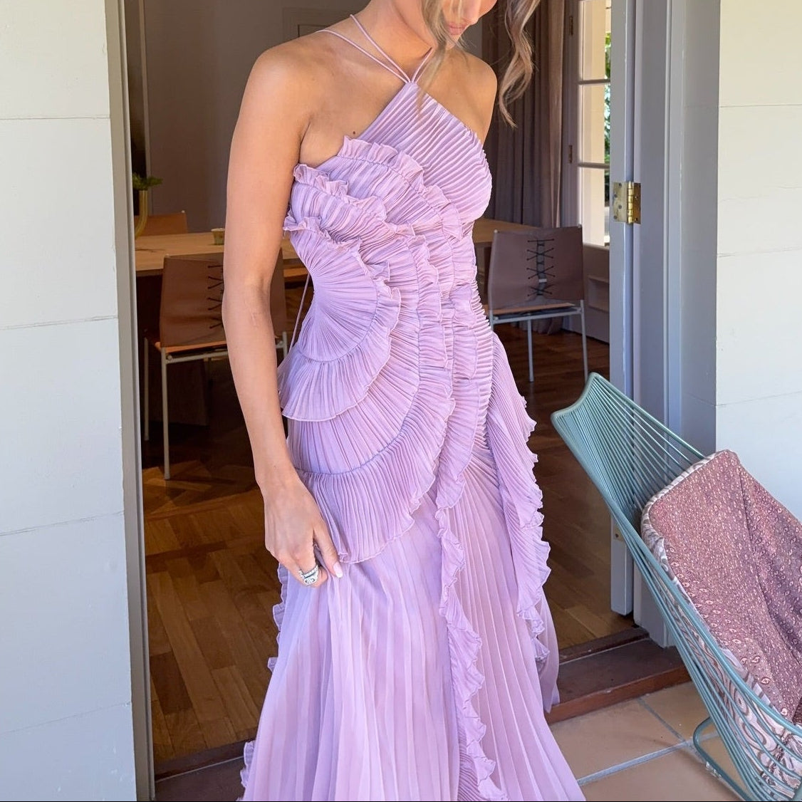 Woman wearing a purple pleated dress standing indoors.