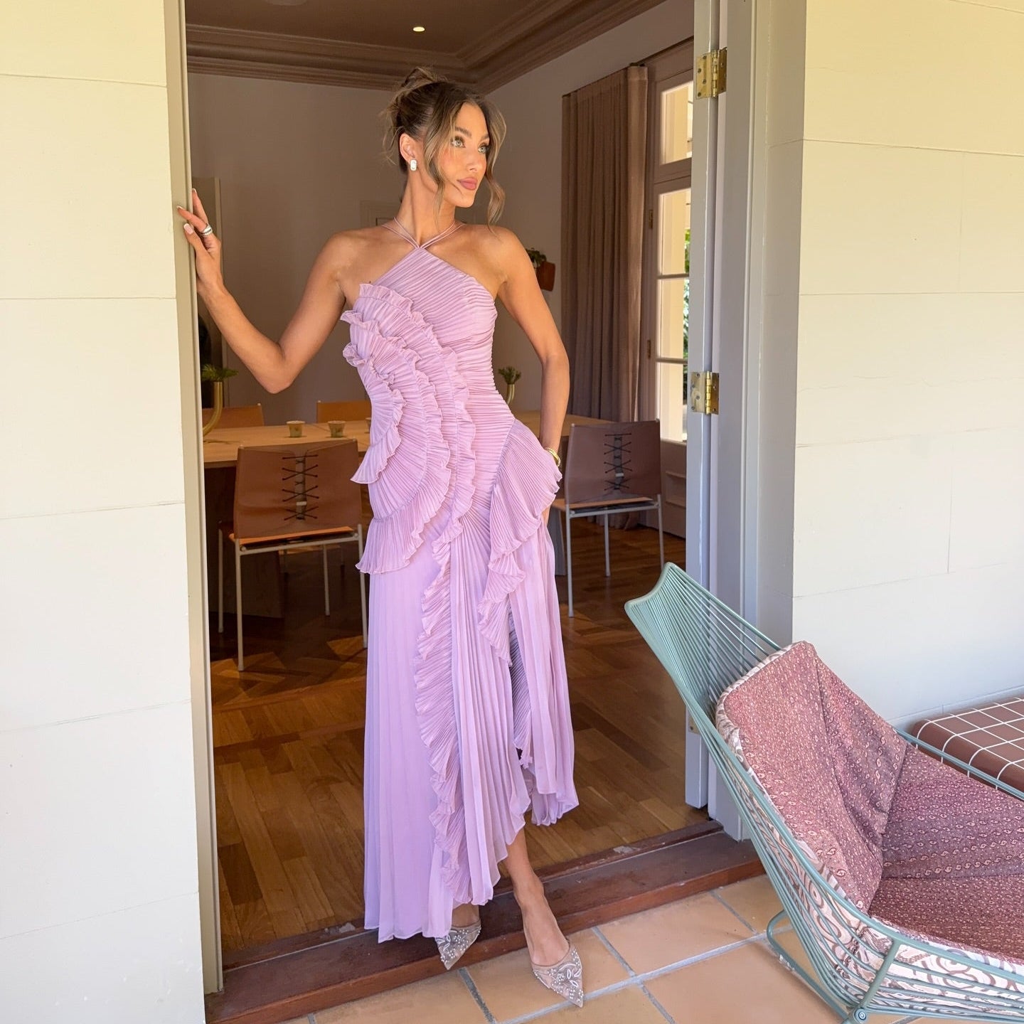 Woman in a lavender one-shoulder dress standing in a doorway.