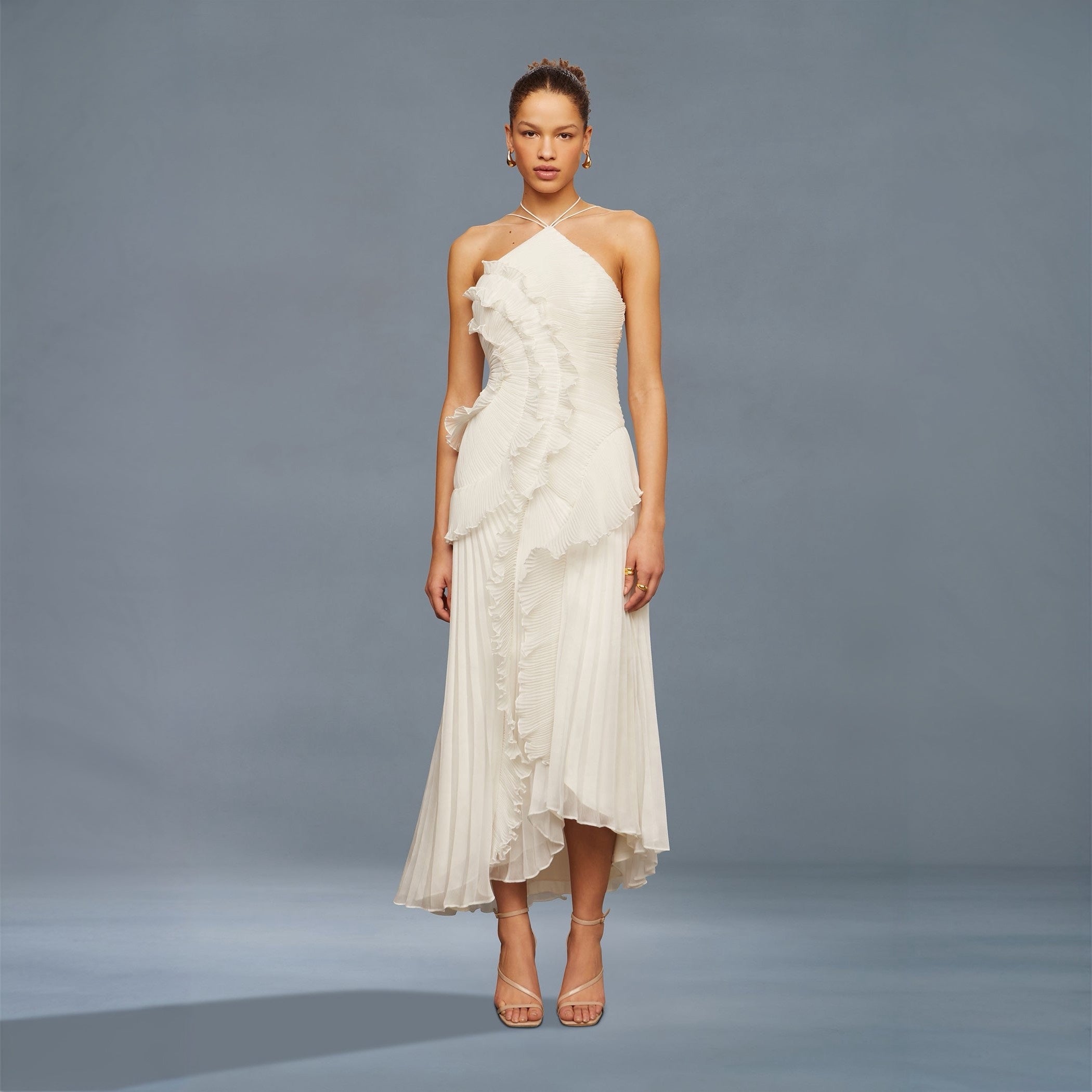 Woman wearing a white one-shoulder dress against a gray background