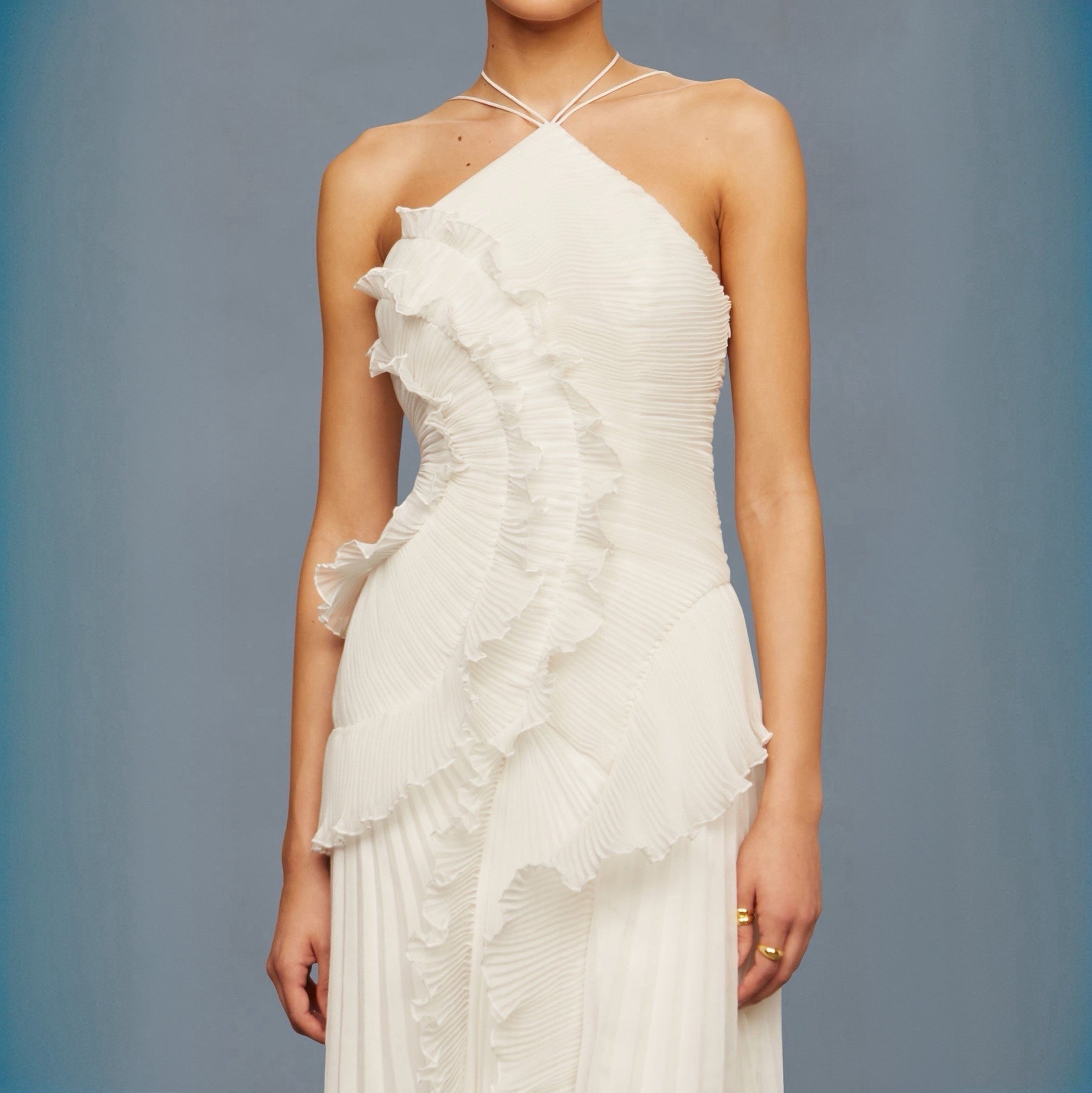 White ruffled dress worn by a model against a gray background
