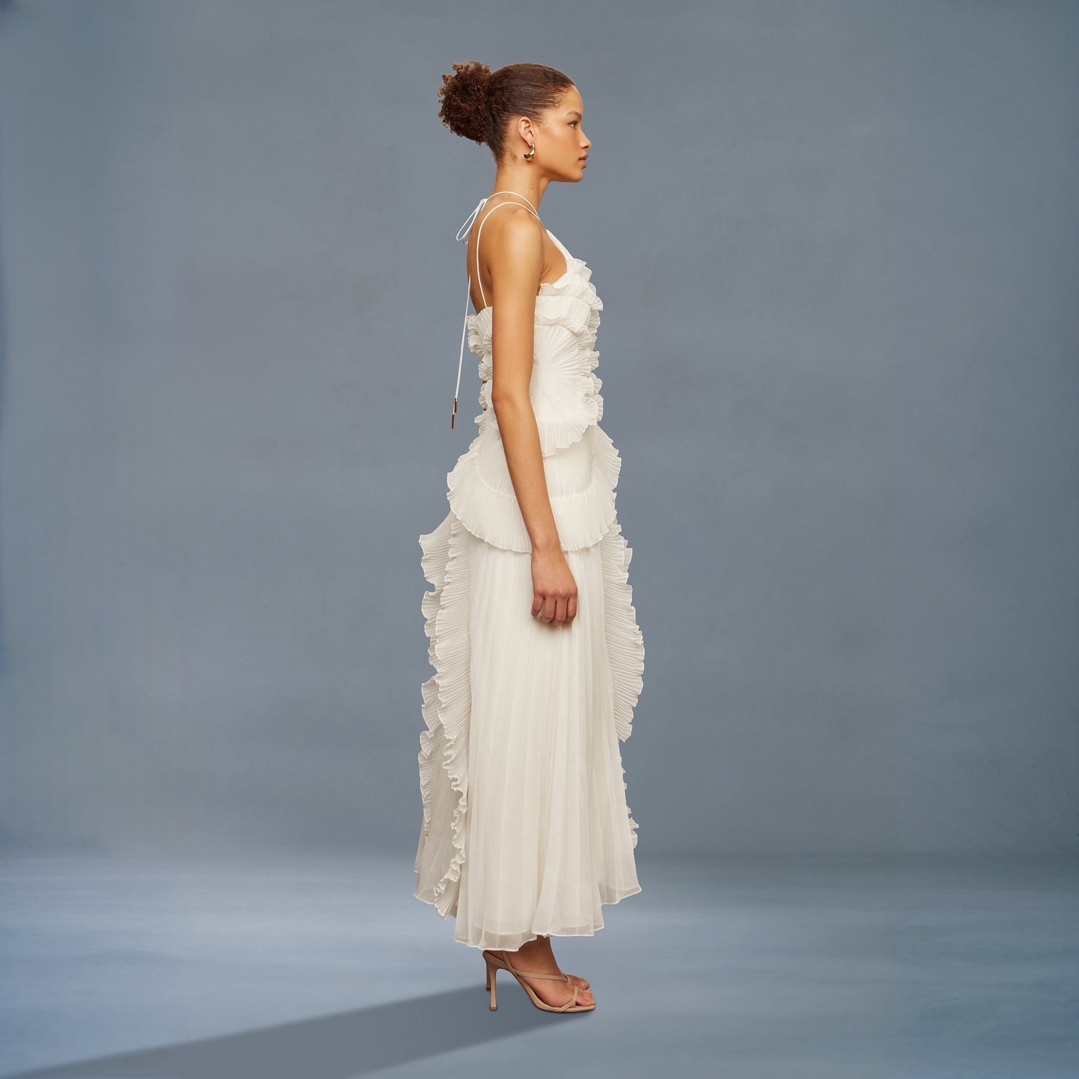 Woman wearing a white ruffled dress against a gray background
