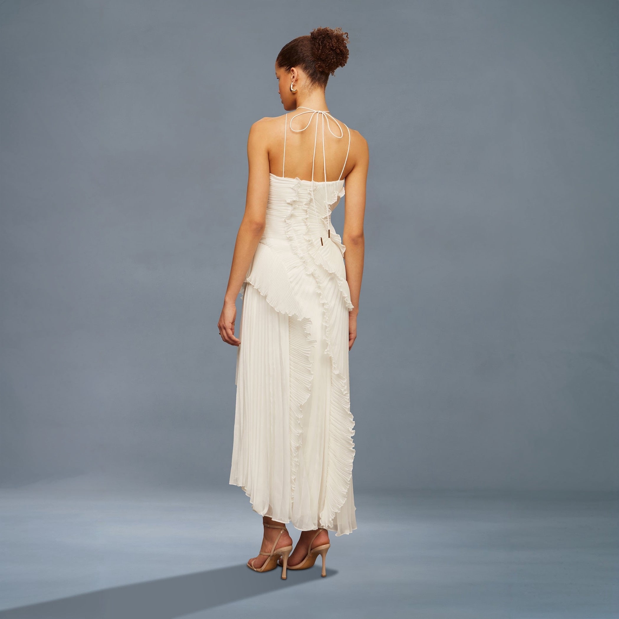 Woman wearing a white floral dress against a gray background