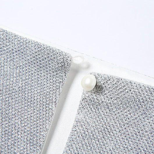 Pearl button on a sparkly top, textured gray background