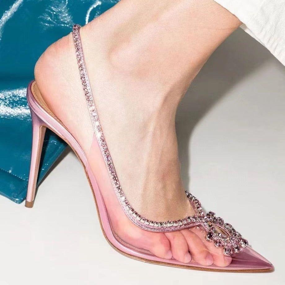 Pink high-heeled sandal with clear strap and rhinestone details on a light background