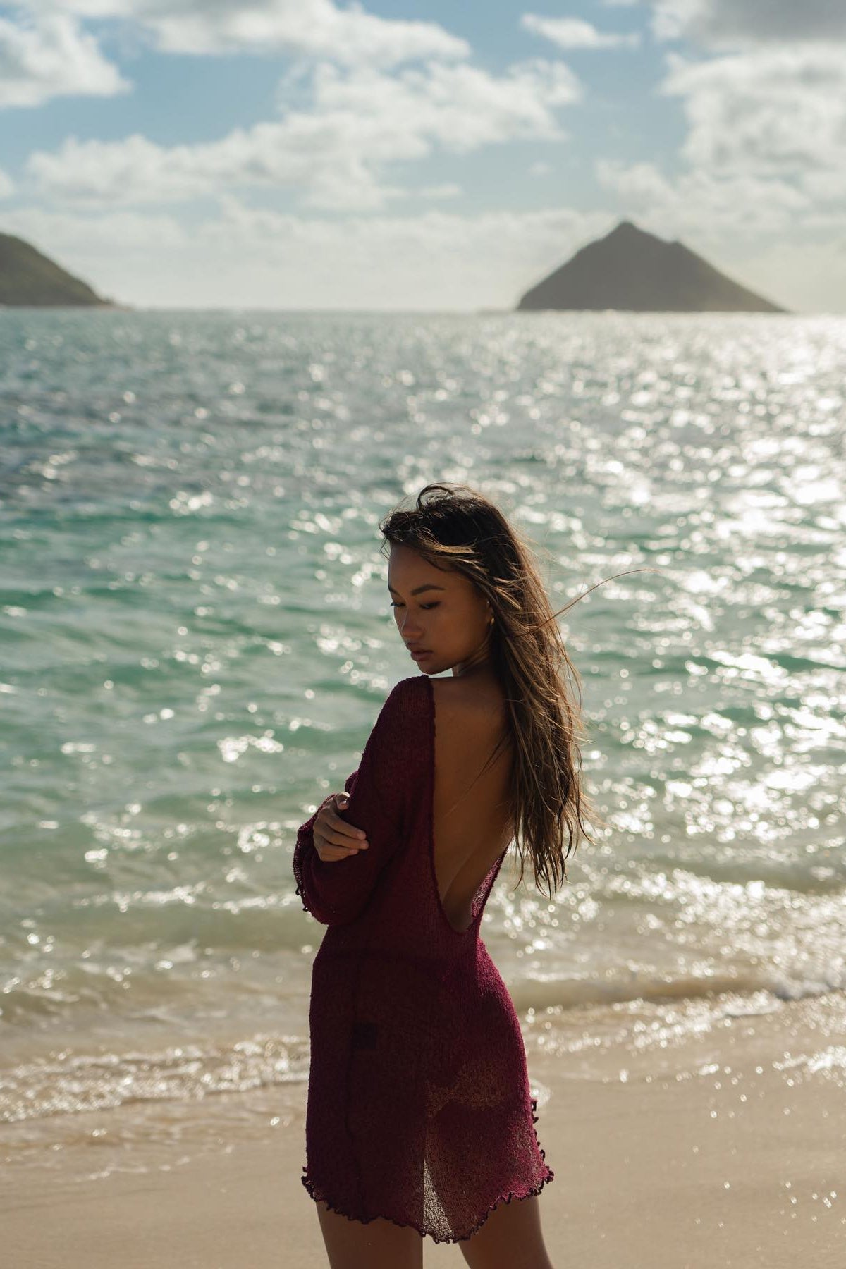 Burgundy open-back knit mini dress with long flared sleeves, warm-toned editorial