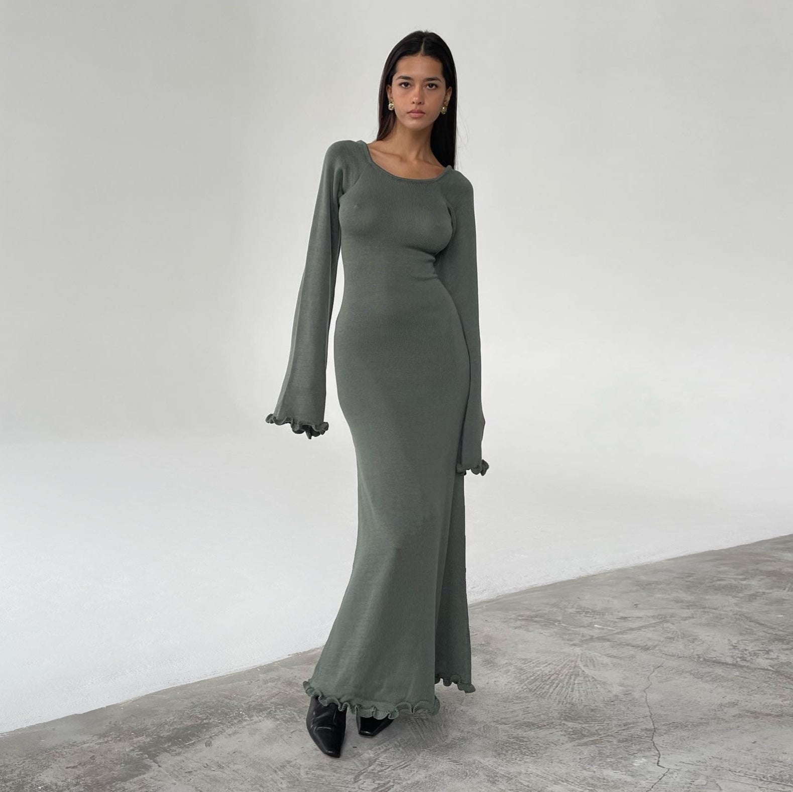 Woman wearing a long green dress standing against a white background