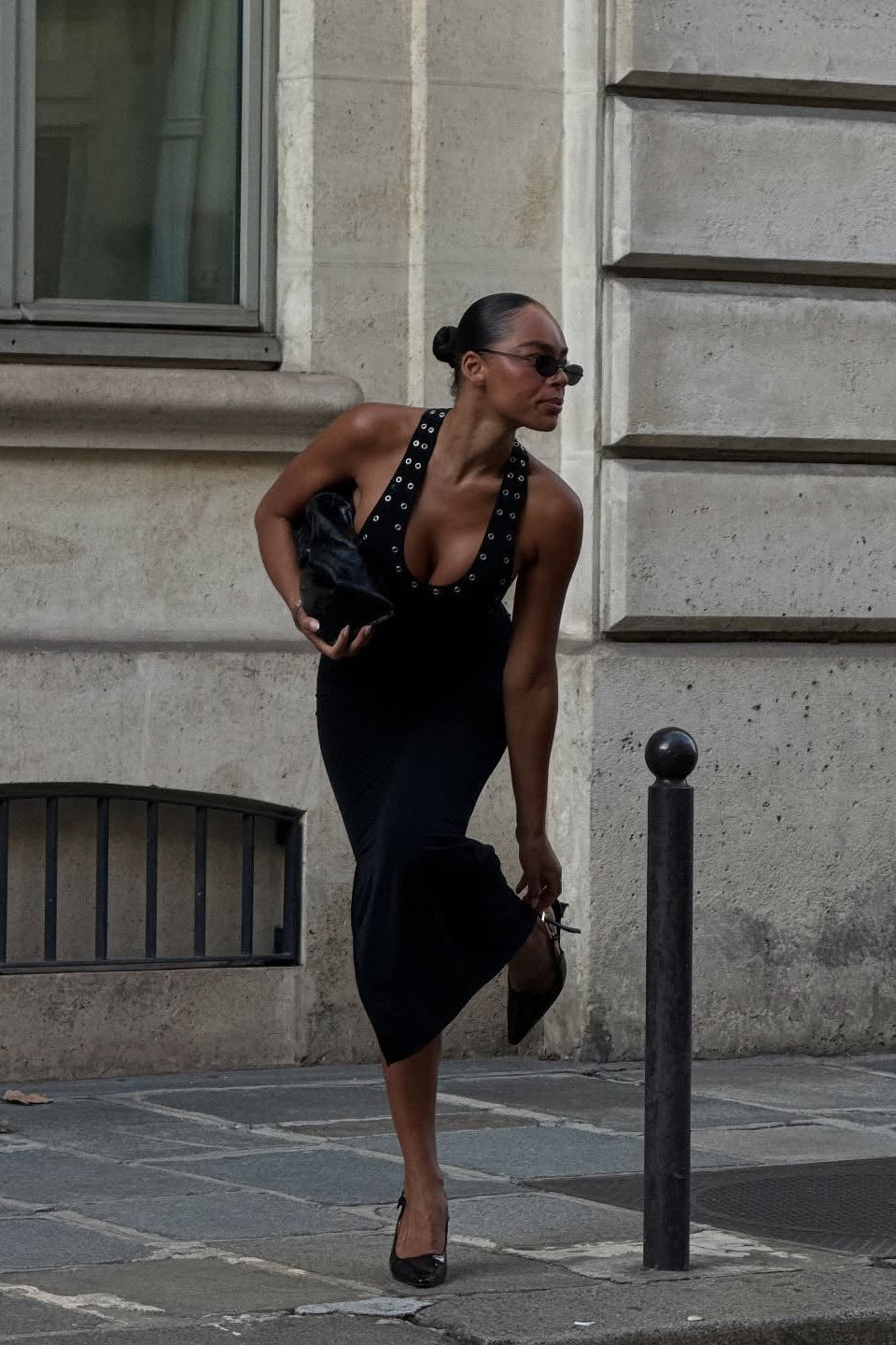 Model in black bodycon midi dress with deep racerback, side view