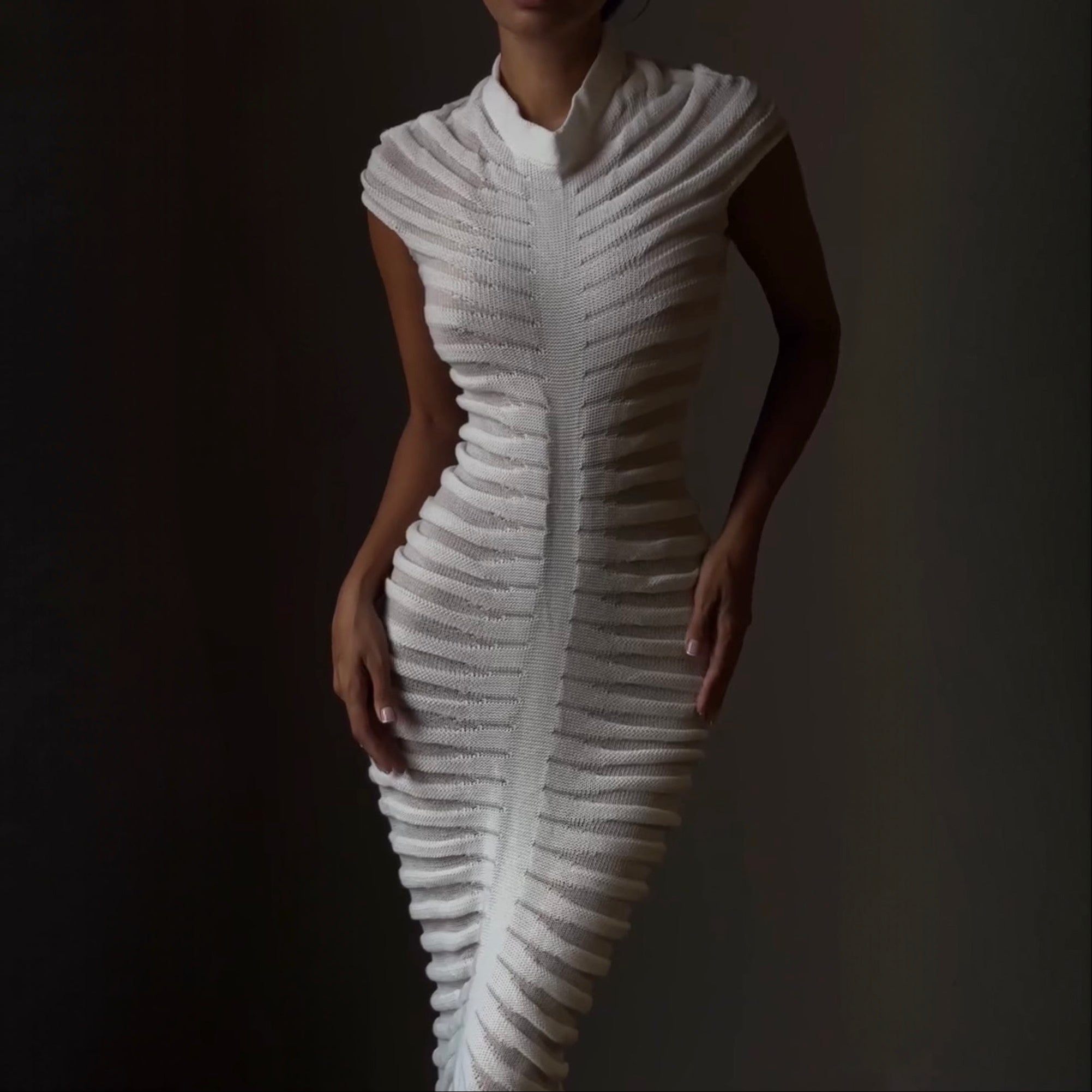 Woman wearing a white, textured dress against a dark background