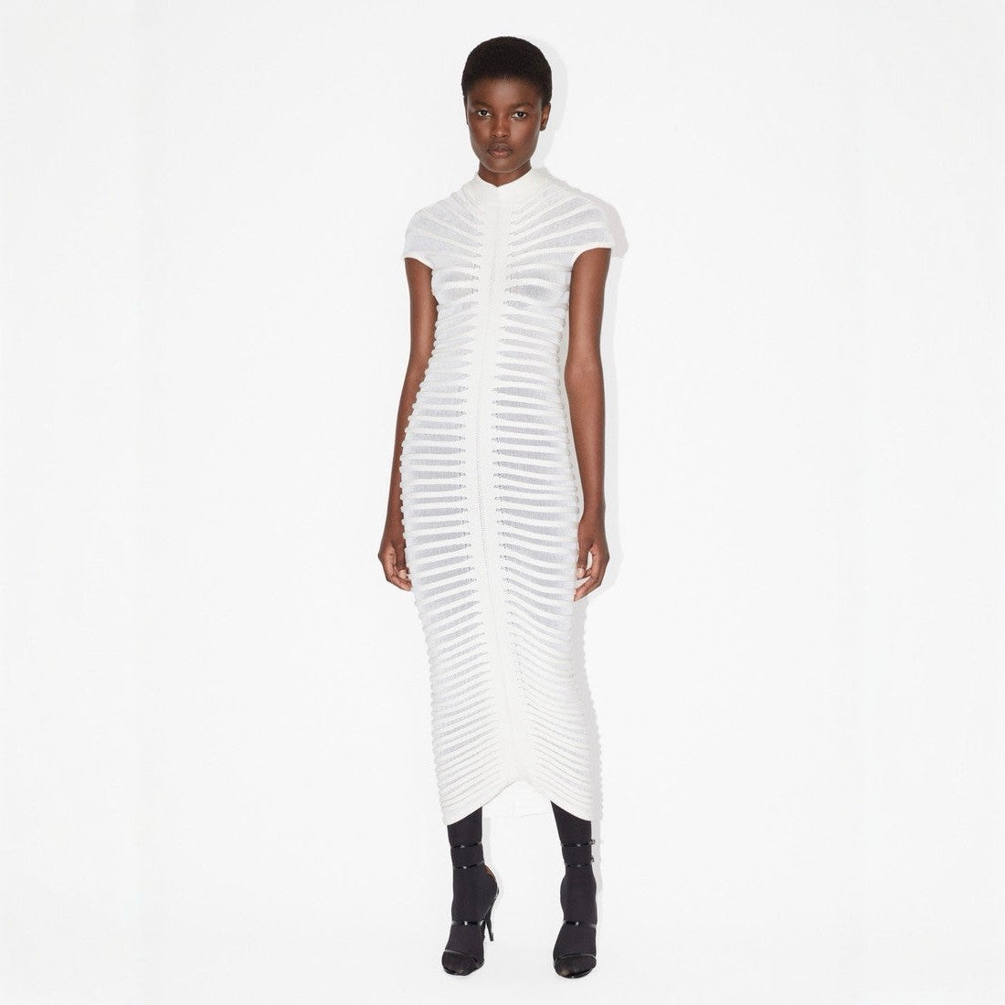 Woman wearing a white dress with a textured pattern on a white background