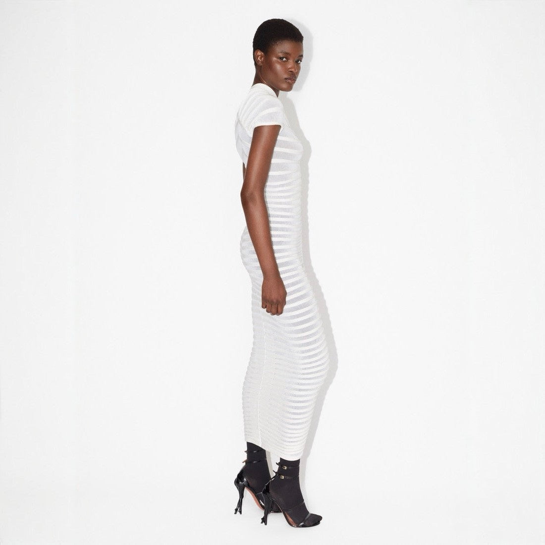 Woman wearing a white ribbed dress on a white background