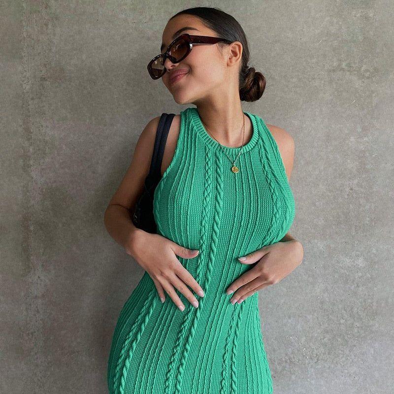 Woman wearing a green knitted dress against a gray background