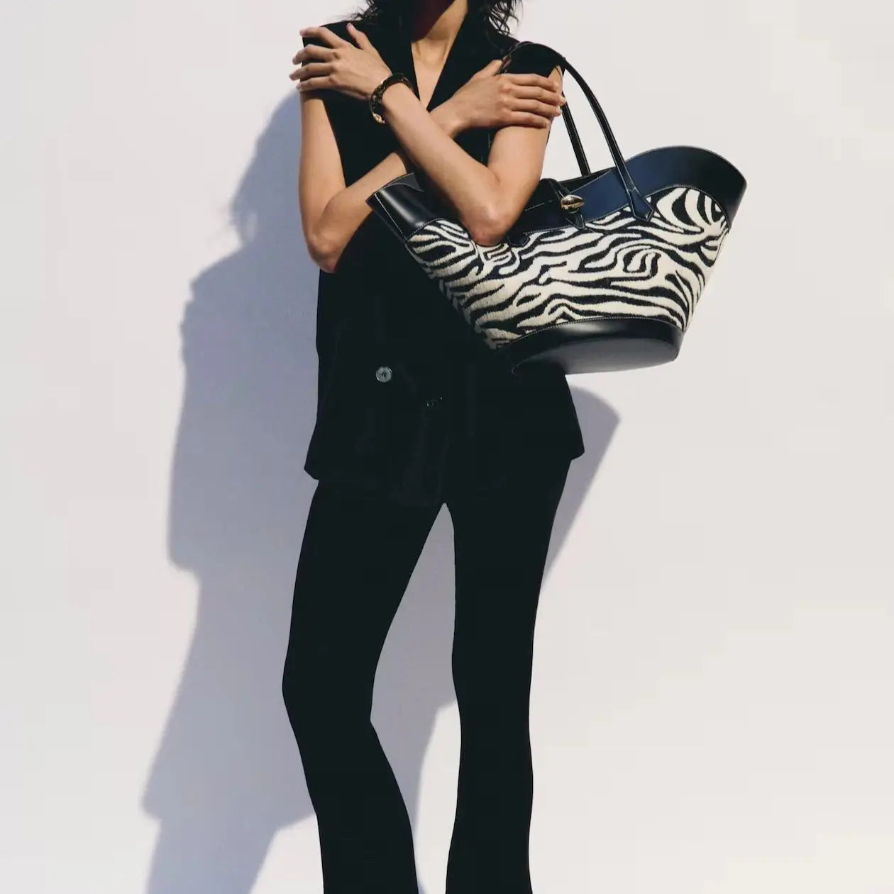 black sleeveless top and flared pants with zebra print statement bag, chic ensemble