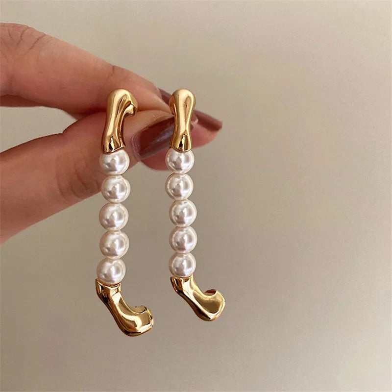 Gold and pearl drop earrings with a unique curved design, statement accessories.